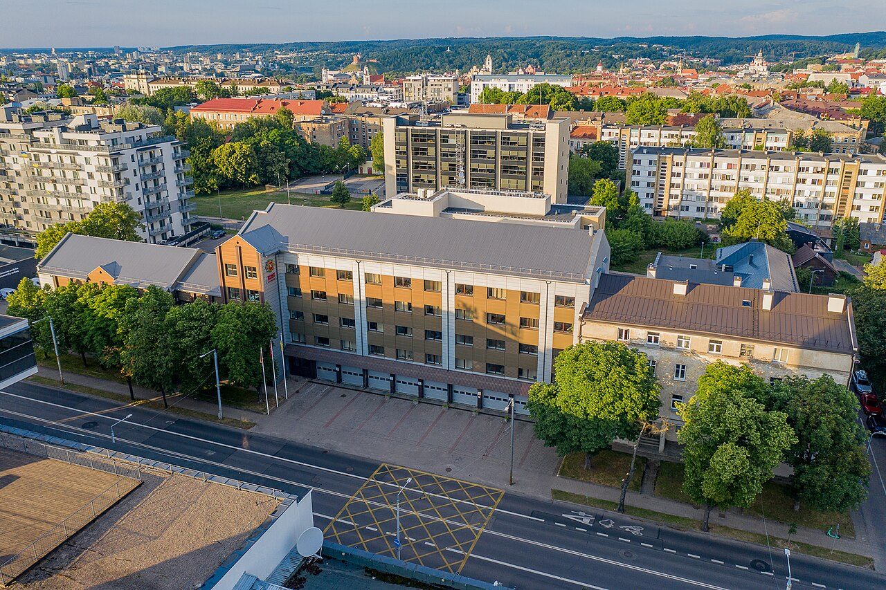 Iš viršaus nufotografuotas keturių aukštų PAGD pastatas su garažų vartais prie gatvės Vilniuje