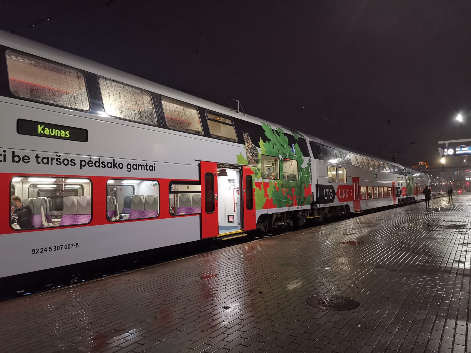 Dviaukštis „LTG Link“ traukinys su švieslente „Kaunas“ prie šlapio Vilniaus geležinkelio stoties perono vakare