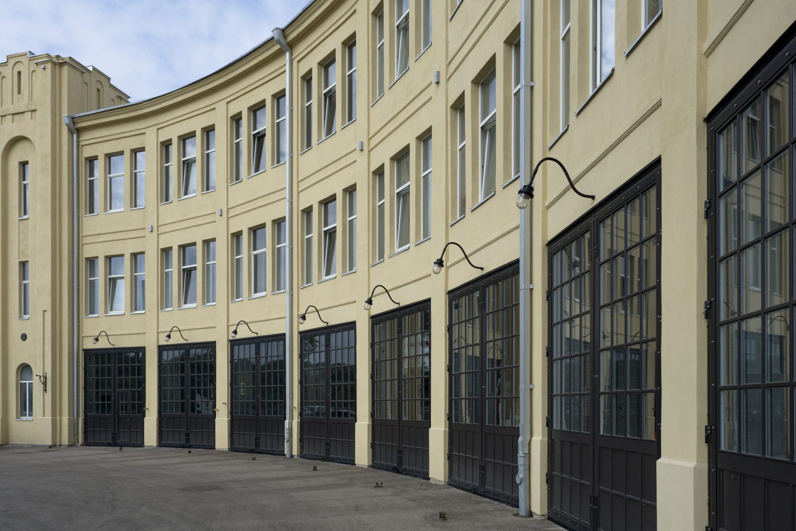 Kauno centrinės gaisrinės lenktas fasadas su tamsiais įstiklintais garažų vartais ir bokštu